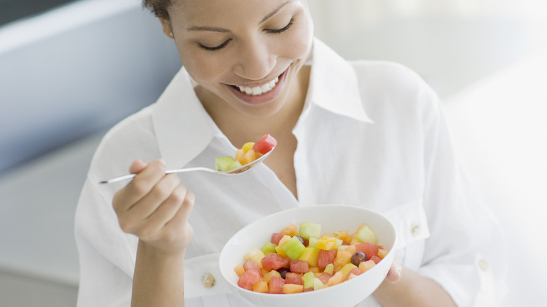 A smiling woman enjoying a fruit salad