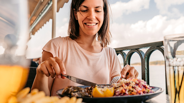 A smiling woman eating seafood outside