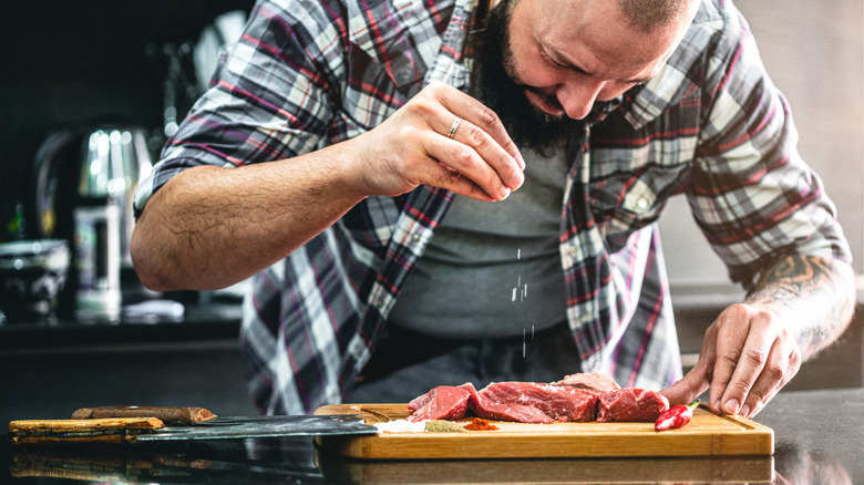 A man seasoning meat before cooking