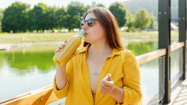 Woman standing outside drinking pineapple juice