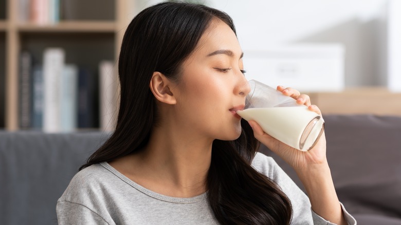 Young woman drinking a glass of oat milk