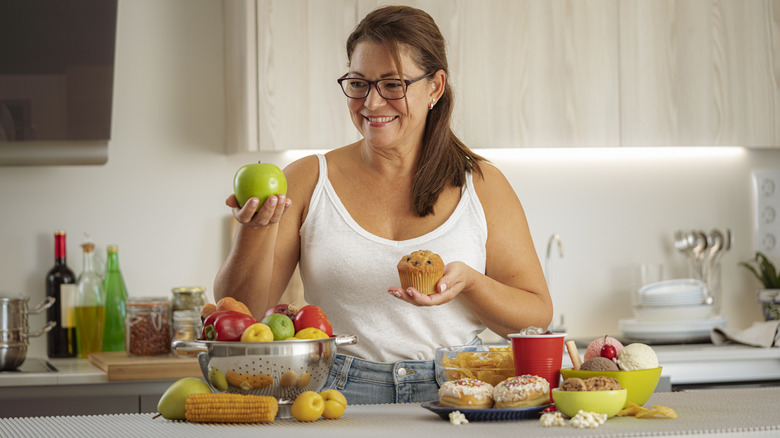 woman holding apple and muffin