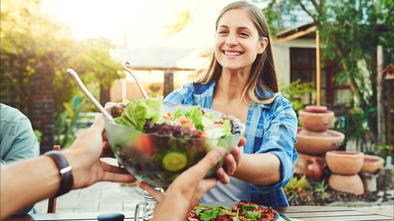 young woman accepts bowl of salad