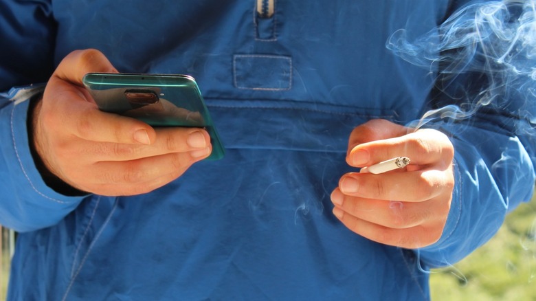 close up man holding lit cigarette