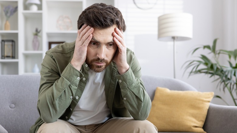 Man sitting on couch looking worried