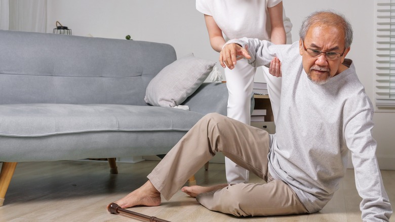 older man being helped up after falling