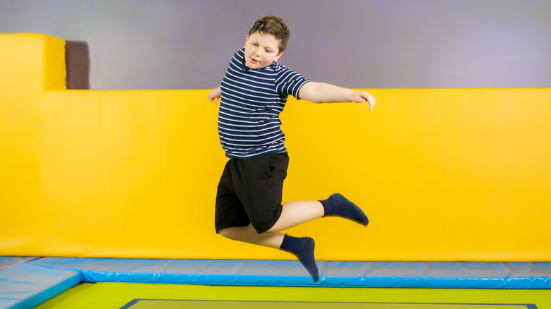 overweight boy jumping on trampoline