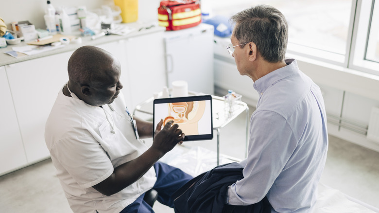 Doctor sitting in front of patient explaining the location of the prostate with a tablet