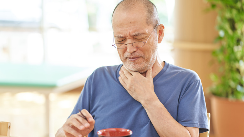 man clutching sore throat