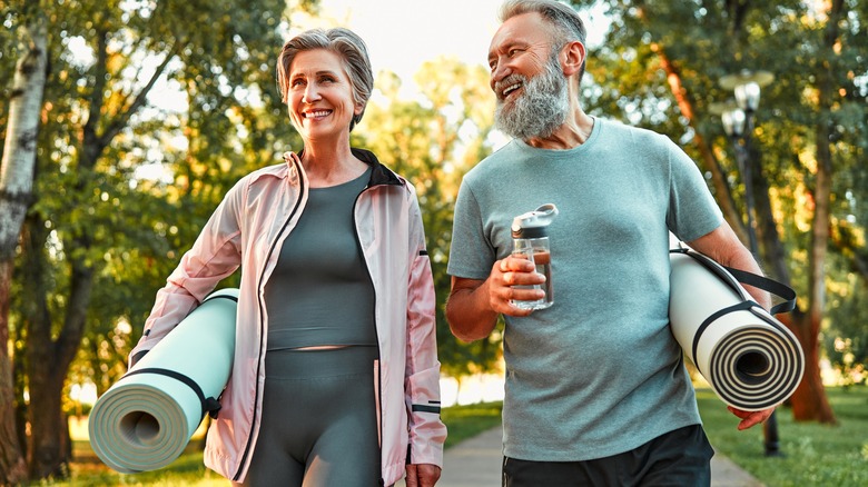 Older couple outside with yoga mats under arms