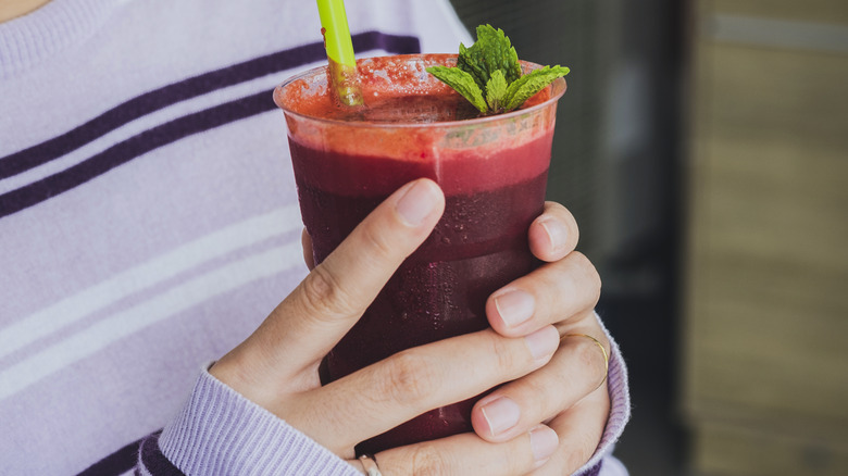 A person holding a glass of beet juice