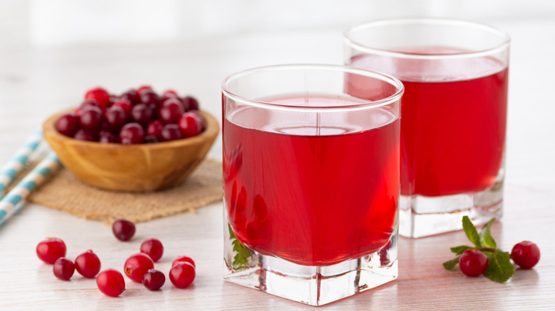 Glasses of cranberry juice with a bowl of cranberries.