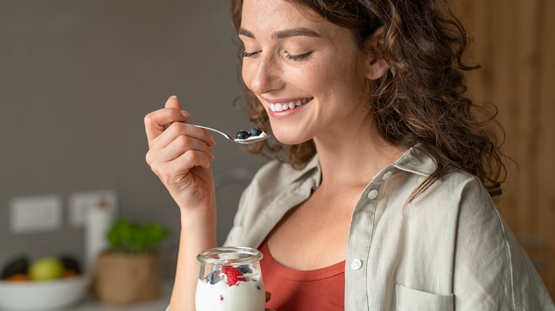 Young woman eating yogurt with blackberries