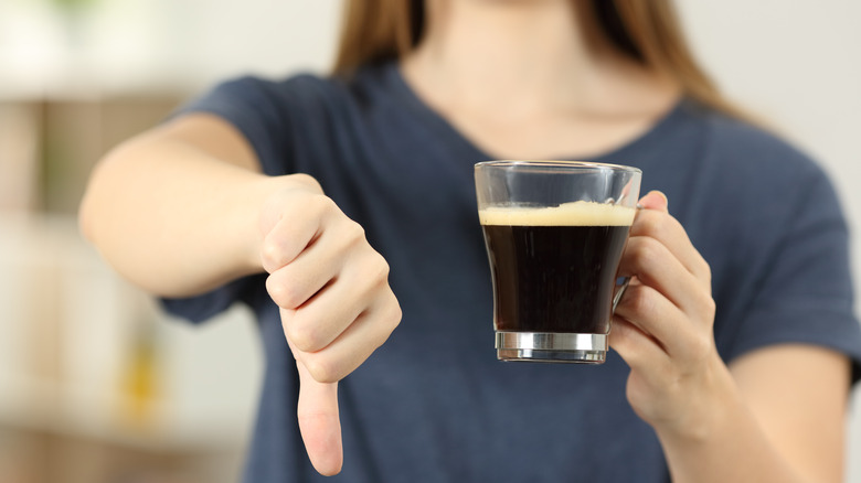 Person putting thumbs down to coffee