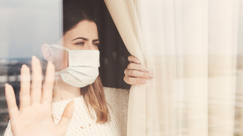 woman in surgical mask quarantining at home