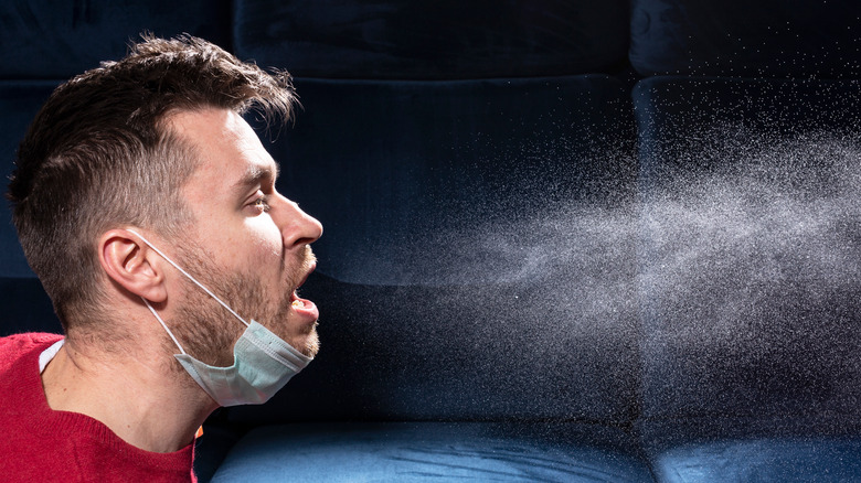 person sneezing out respiratory droplets