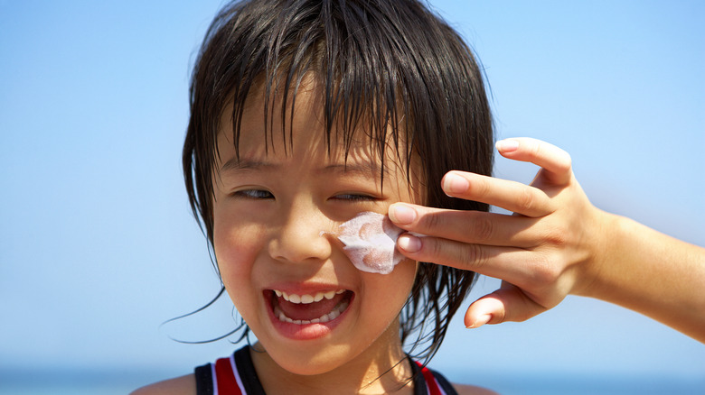 child getting sunscreen applied