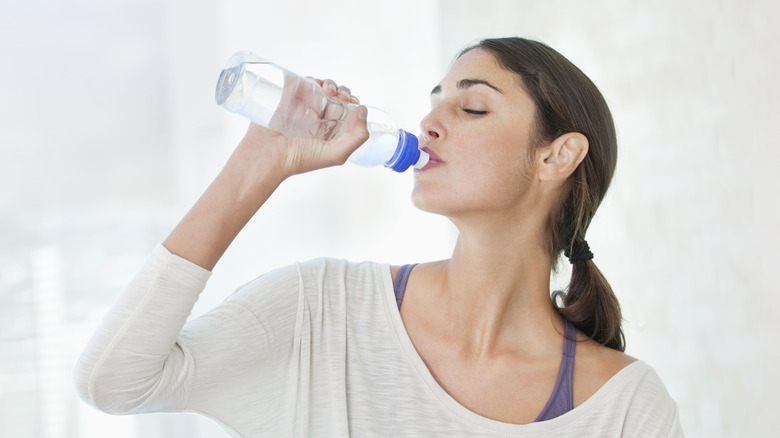 woman drinking out of a plastic water bottle