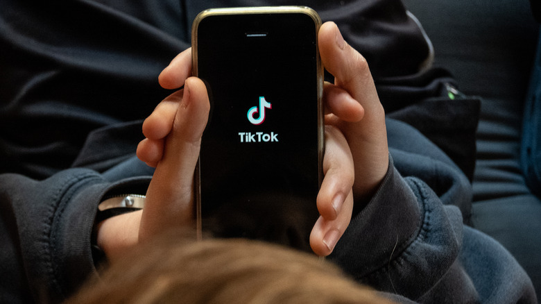 Teen holding smartphone opening TikTok app