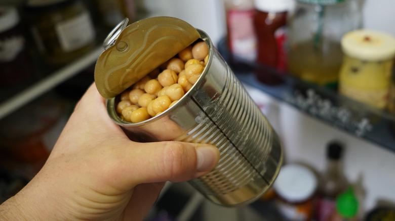 woman's hand holding open can of chickpeas