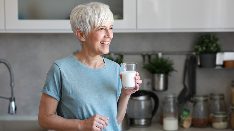 An older woman drinking a glass of milk