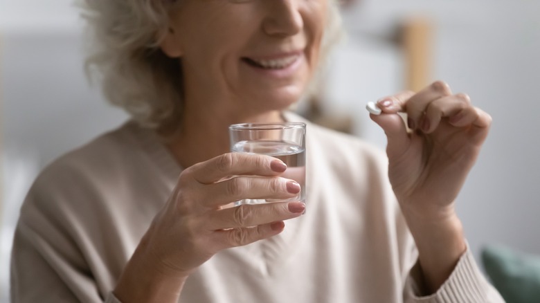 Smiling older woman taking medication