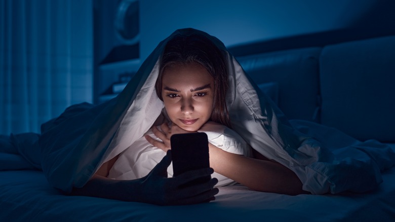 woman looking at her phone in her bed at night