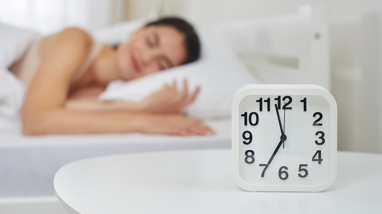 woman sleeping with alarm clock by her bed