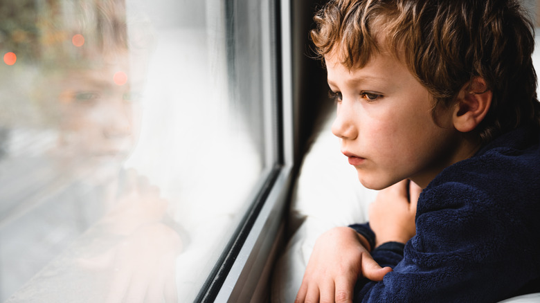 Young boy looking out window