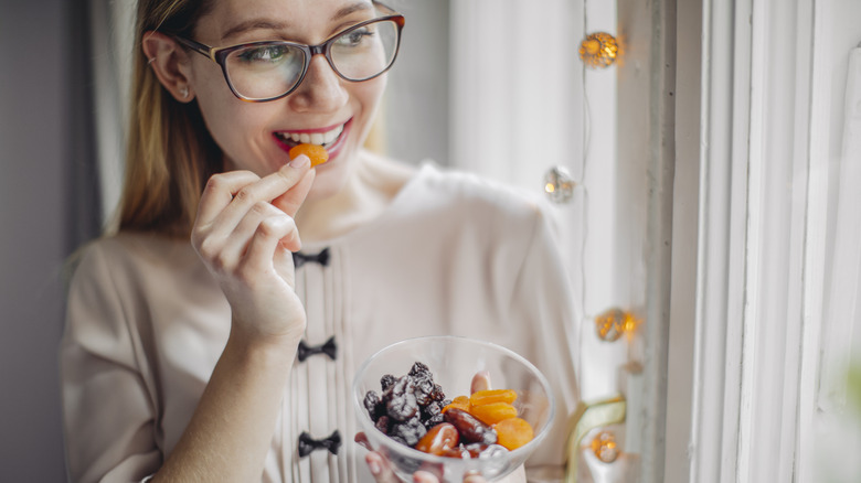 woman holding bowl of dried fruits