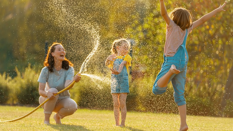 family playing with a sprinkler outdoors