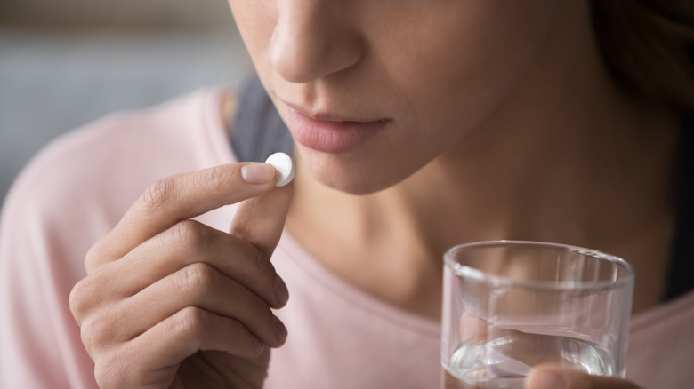 close up of a woman swallowing a pill with water