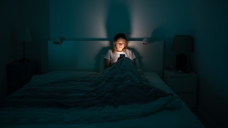 Woman using phone in bed