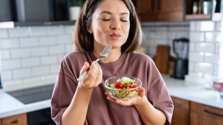 A woman enjoying a salad in her kitchen