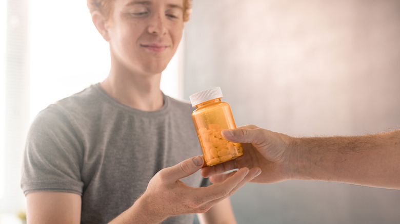 person being handed pill bottle