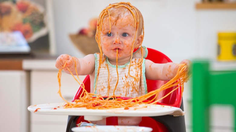 baby covered in spaghetti and sauce
