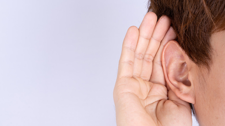 hand cupping ear to show hearing loss 