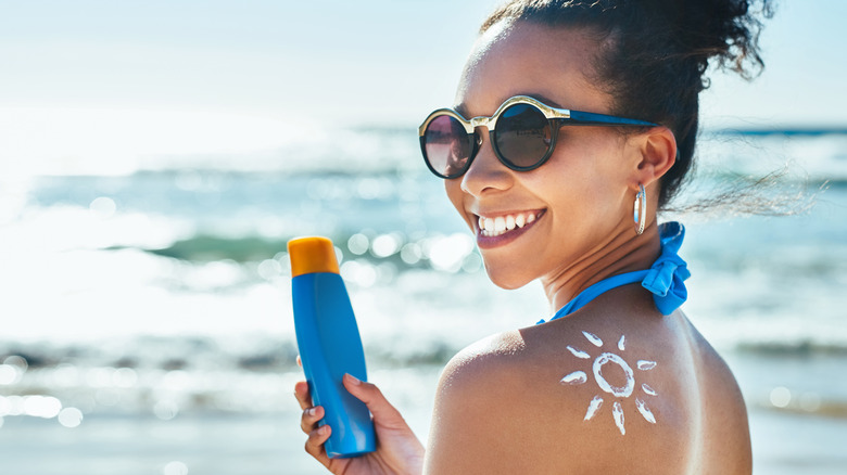 Woman wearing sunglasses and holding sunscreen