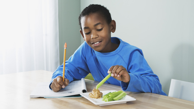 Kid eating snack and working on homework