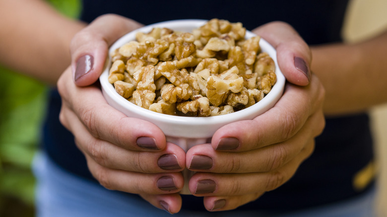 Hands holding bowl of walnuts