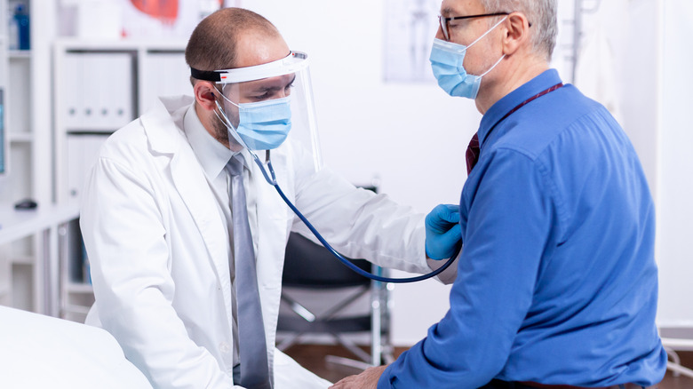 Doctor checking man's heart