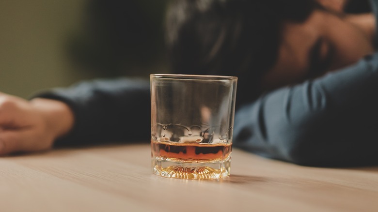 Man sleeping next to glass of alcohol