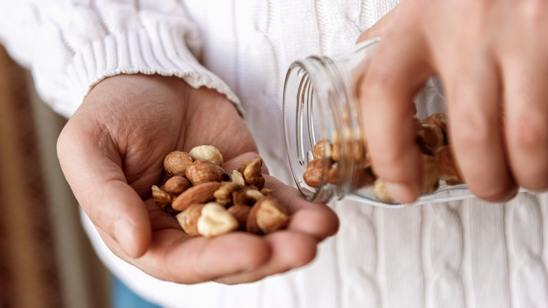 man pouring mixed nuts into hand