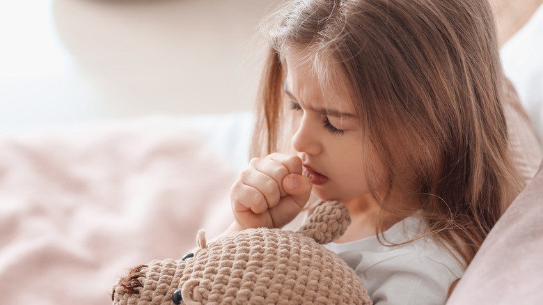 Little girl coughing with closed eyes 