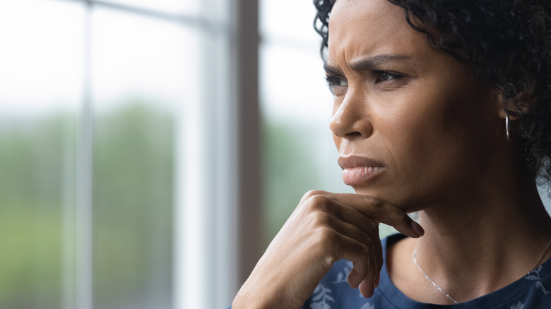 upset Black woman looking out window