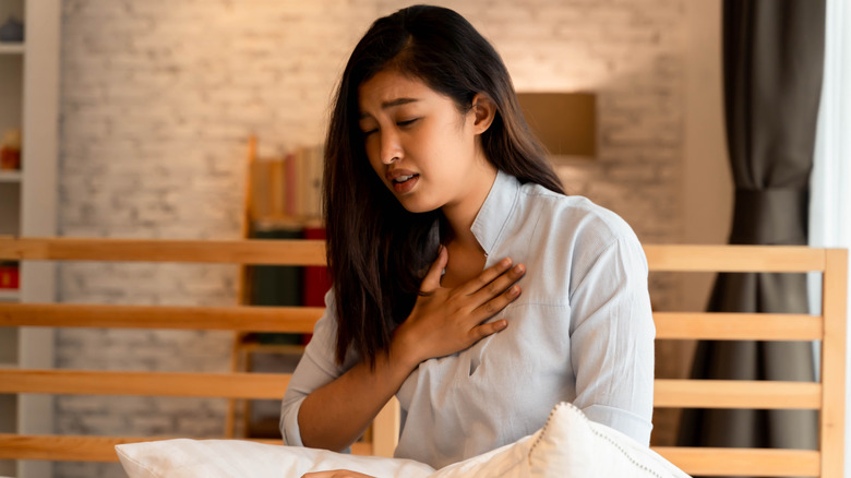 A women sitting up in bed with chest pain