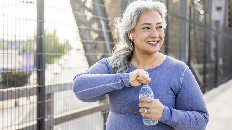 middle age woman holding a water bottle after a workout