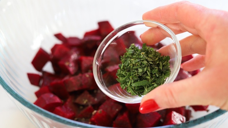 hand adding rosemary to beets