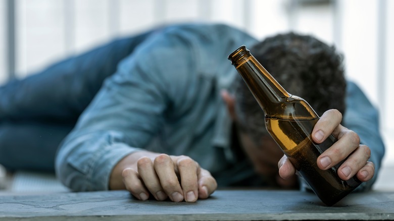 drunk man passed out holding a beer