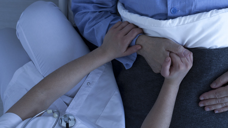 hospice nurse holding elderly patient's hand